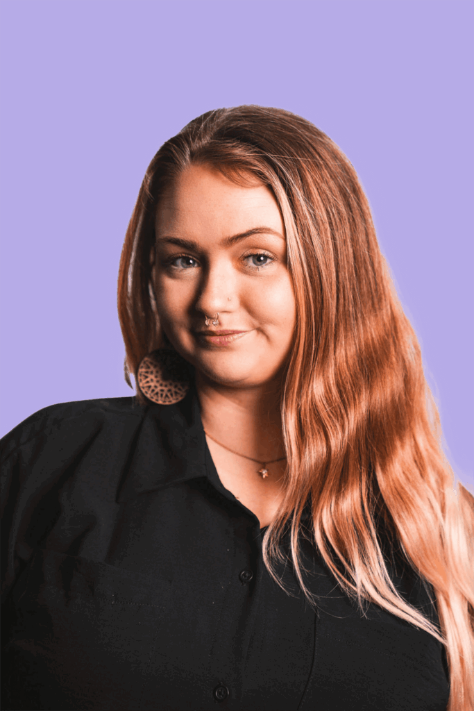 A photo of a blonde woman dressed in black with a purple background.
